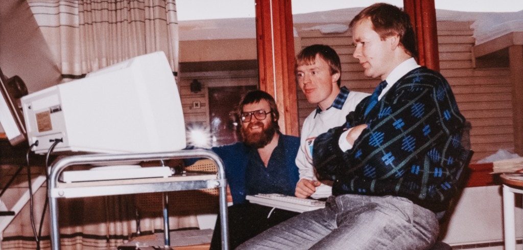 Bilde fra 80-tallet av tre menn foran en datamaskin