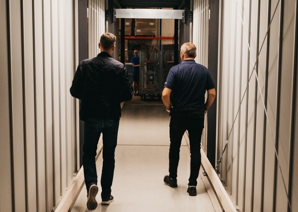 To menn går ned gjennom en spesiallagd tunnel i AutoStore-lageret til GS Bildeler