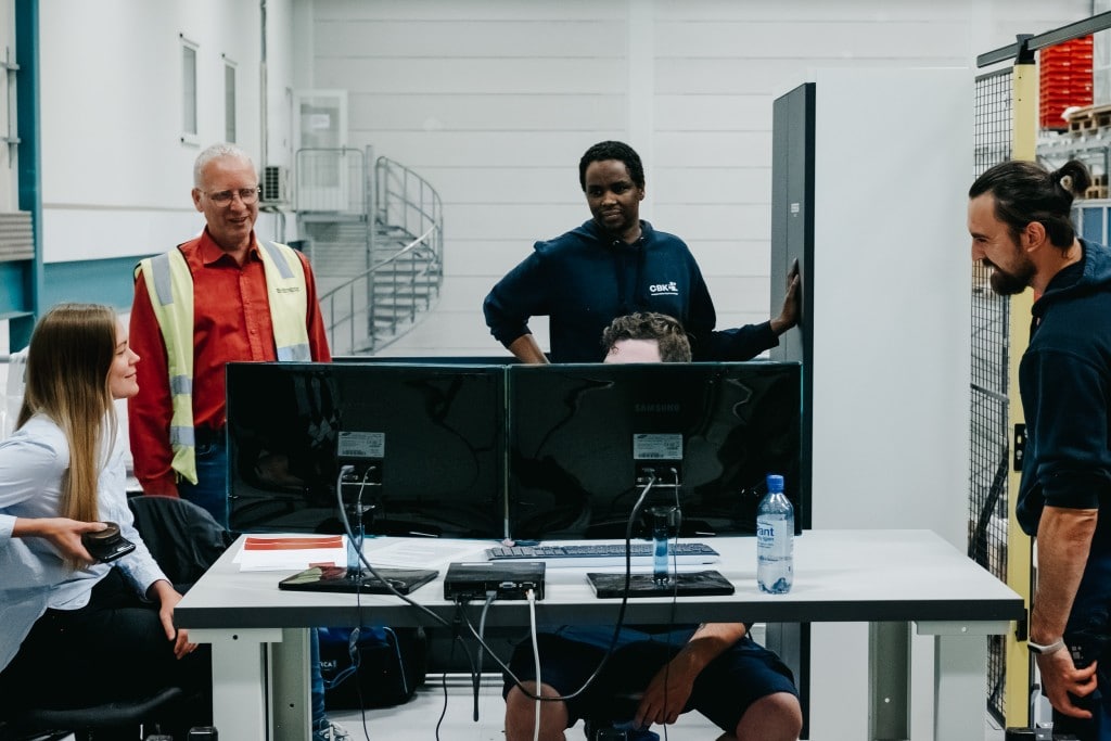 Fem personer jobber sammen foran en dataskjerm for å lære hvordan de drifter sitt nye AutoStore-system.