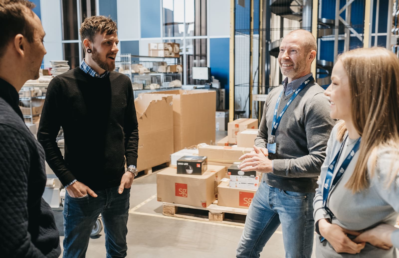 To ansatte i Element Logic prater med to smilende kunder i et lager.