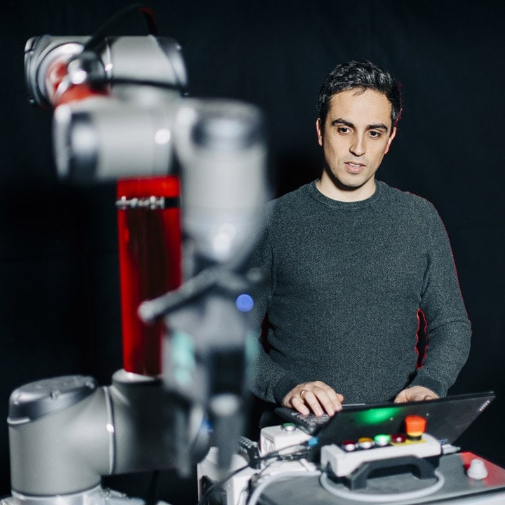 En mann programmerer og styrer en robotarm fra Element Logic og Autostore