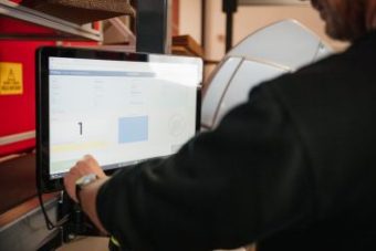 En mann bruker en berøringsskjerm for å fullføre ordre i et AutoStore-system.